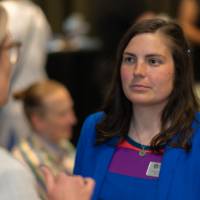 Woman in striped dress listens to another person talk